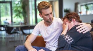 een medewerker die een troostende schouder biedt aan een vedrietige vrouw