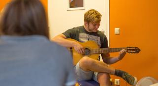 Vrouw kijkt naar man die gitaar speelt in de muziektherapie