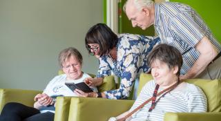 Vrouw laat iets zien op haar smartphone aan een paar mensen