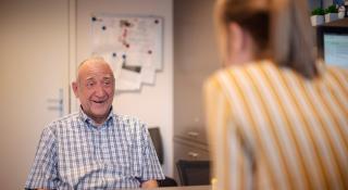 Lachende oudere man in gesprek met een vrouw