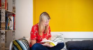 Jonge vrouw leest een boek op haar bed