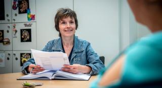 Een collega in gesprek met iemand terwijl ze een papier vasthoudt