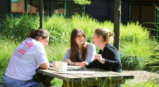 Drie mensen keuvelend op een bank