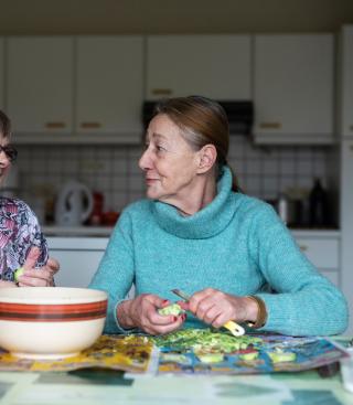 Twee vrouwen doen een babbeltje terwijl ze groenten snijden