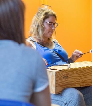 Vrouw speelt instrument tijdens de muziektherapie terwijl er iemand luisterd