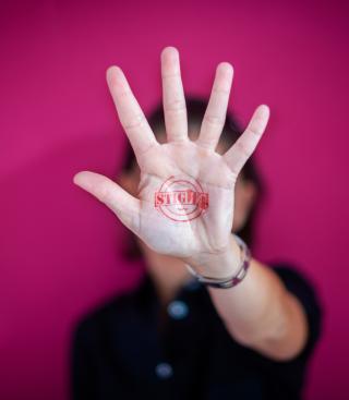 Persoon die hand uitsteekt voor het gezicht met stigWa-stempel op de handpalm