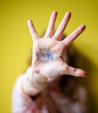 Vrouw die hand uitsteekt voor het gezicht met stigWa-stempel op de handpalm