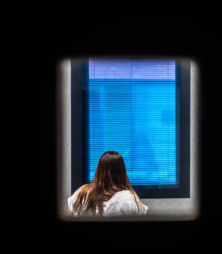 Vrouw kijkt uit het raam van de afzonderingskamer