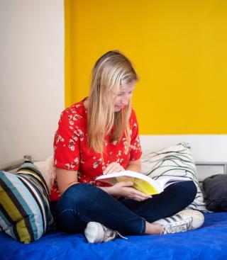 Jonge vrouw leest een boek op haar bed