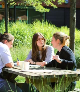 Drie mensen keuvelend op een bank